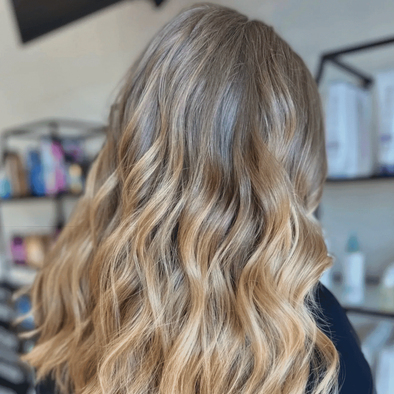 Wavy blonde hair with soft curls in a salon setting.