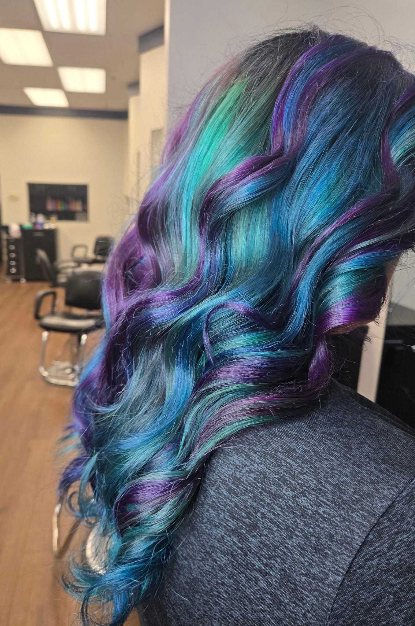 Multicolored hair with vibrant blue, purple, and green hues in a salon setting.