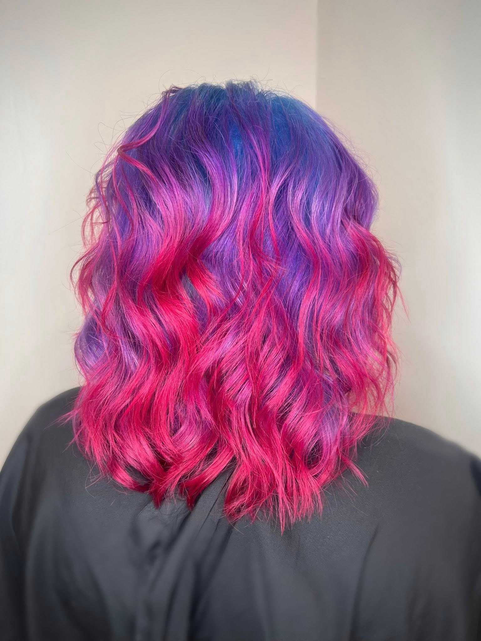 Vibrant pink and purple wavy hair against a plain background.