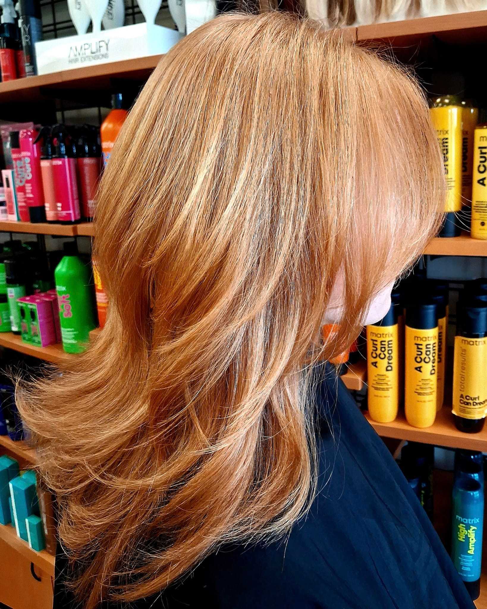 Stylish layered haircut with blonde highlights in a salon setting.