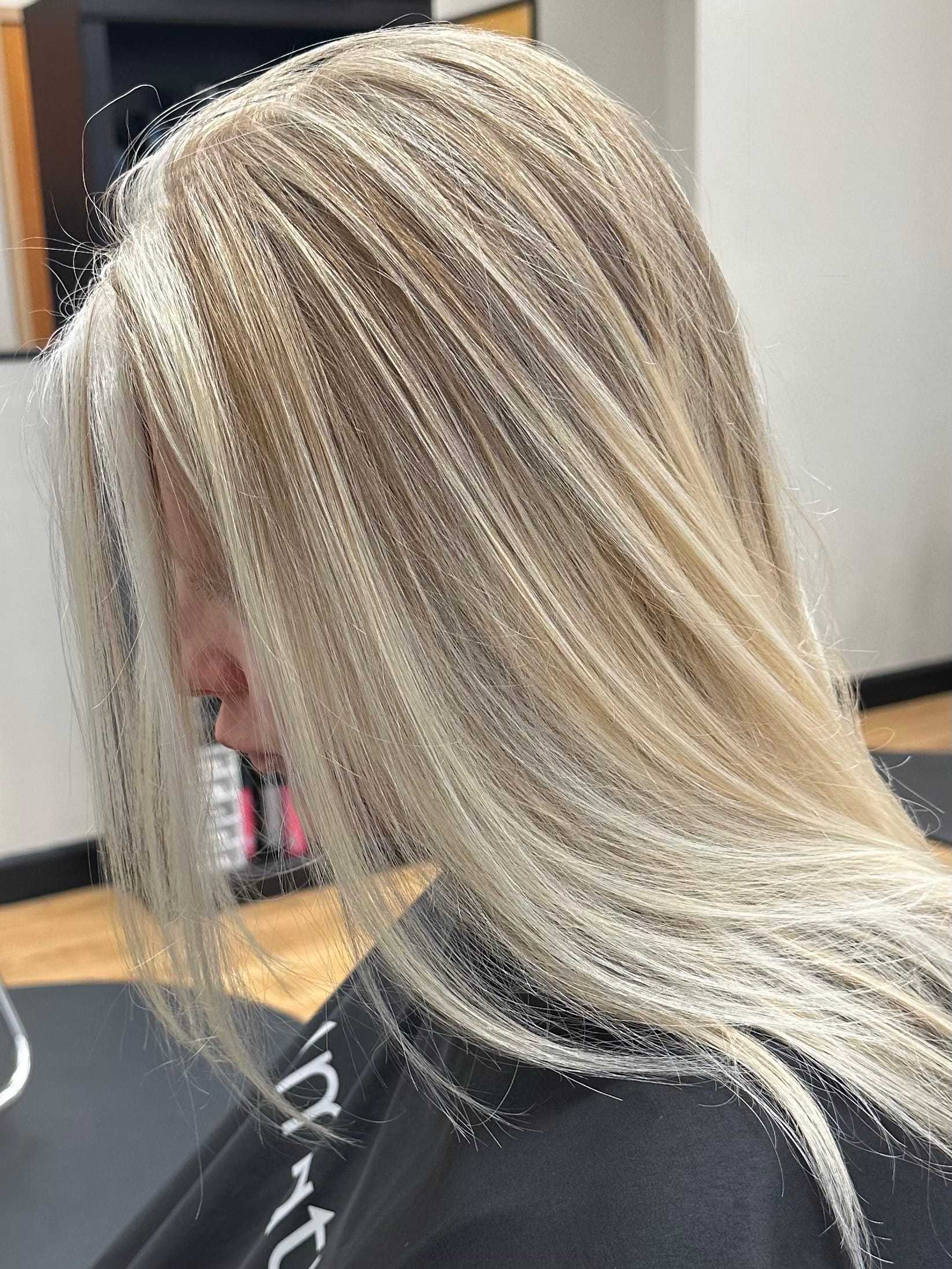 Blonde hair with highlights, side profile in salon setting.