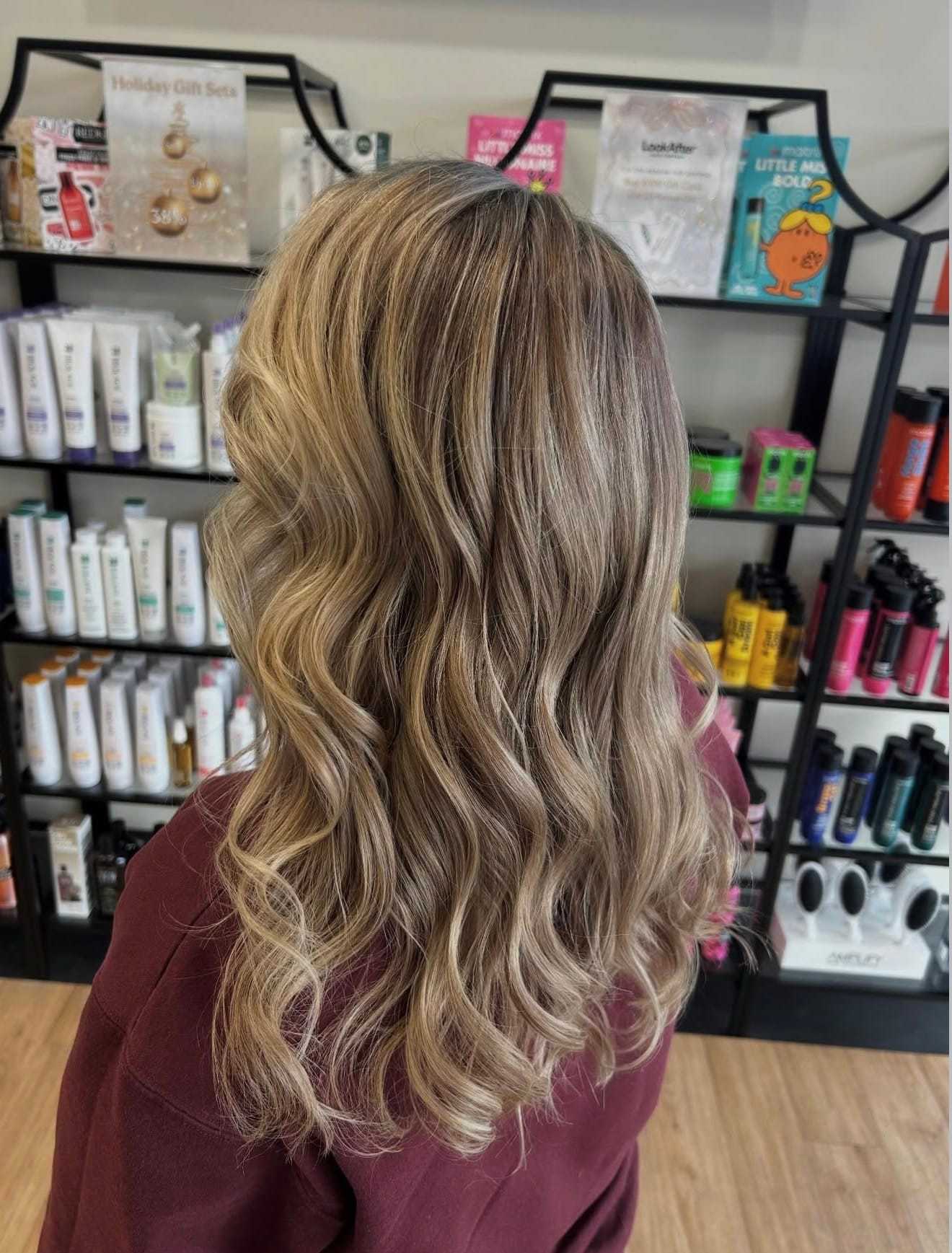 Wavy blonde hair in salon with haircare products on display.