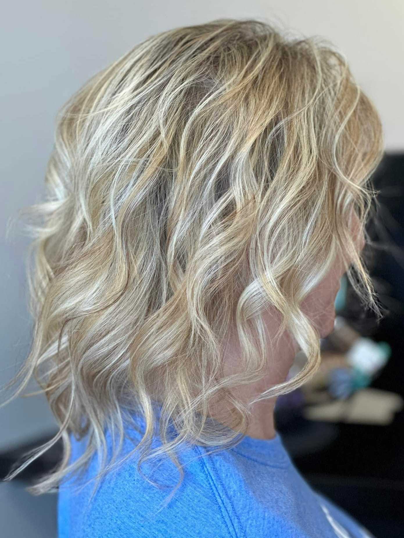 Short, wavy blonde hairstyle with subtle highlights.