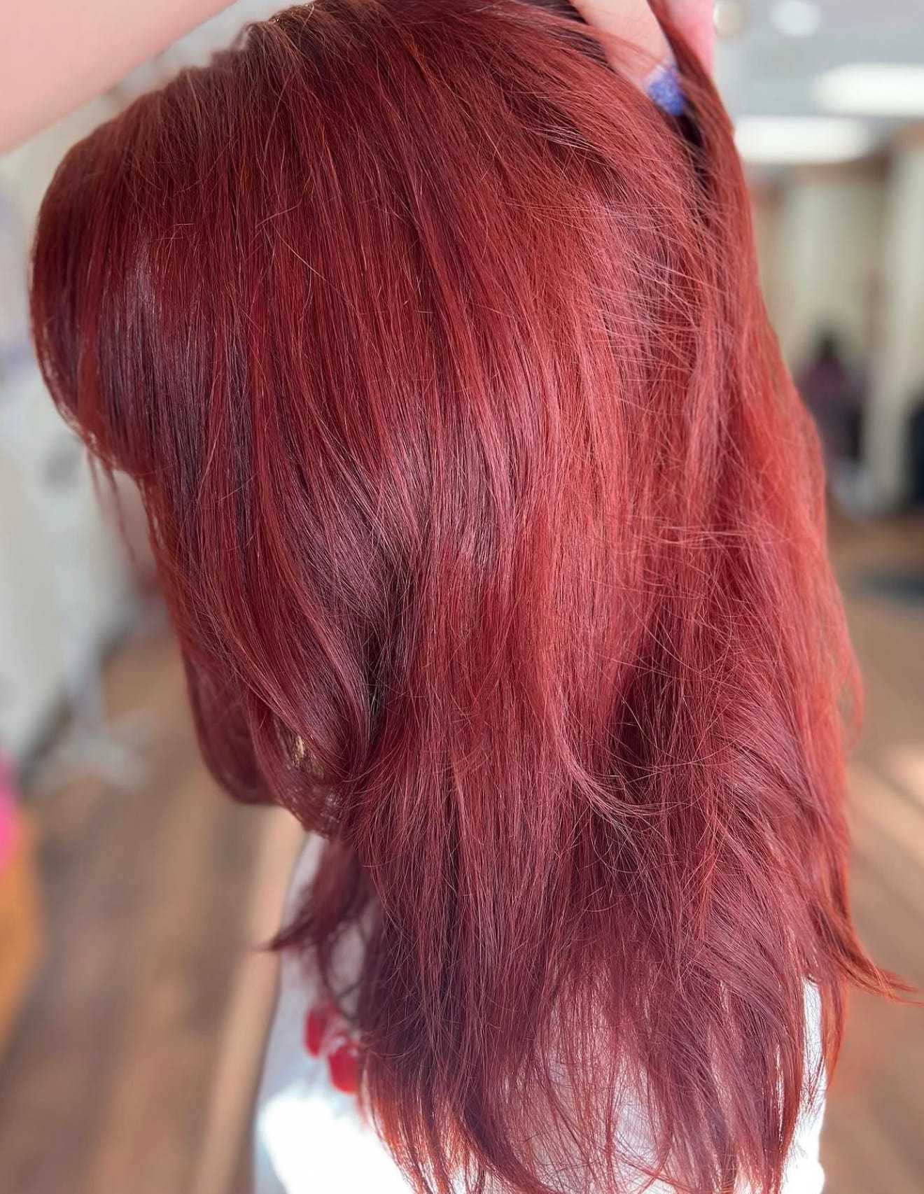 Red hair with vibrant highlights, styled softly indoors.