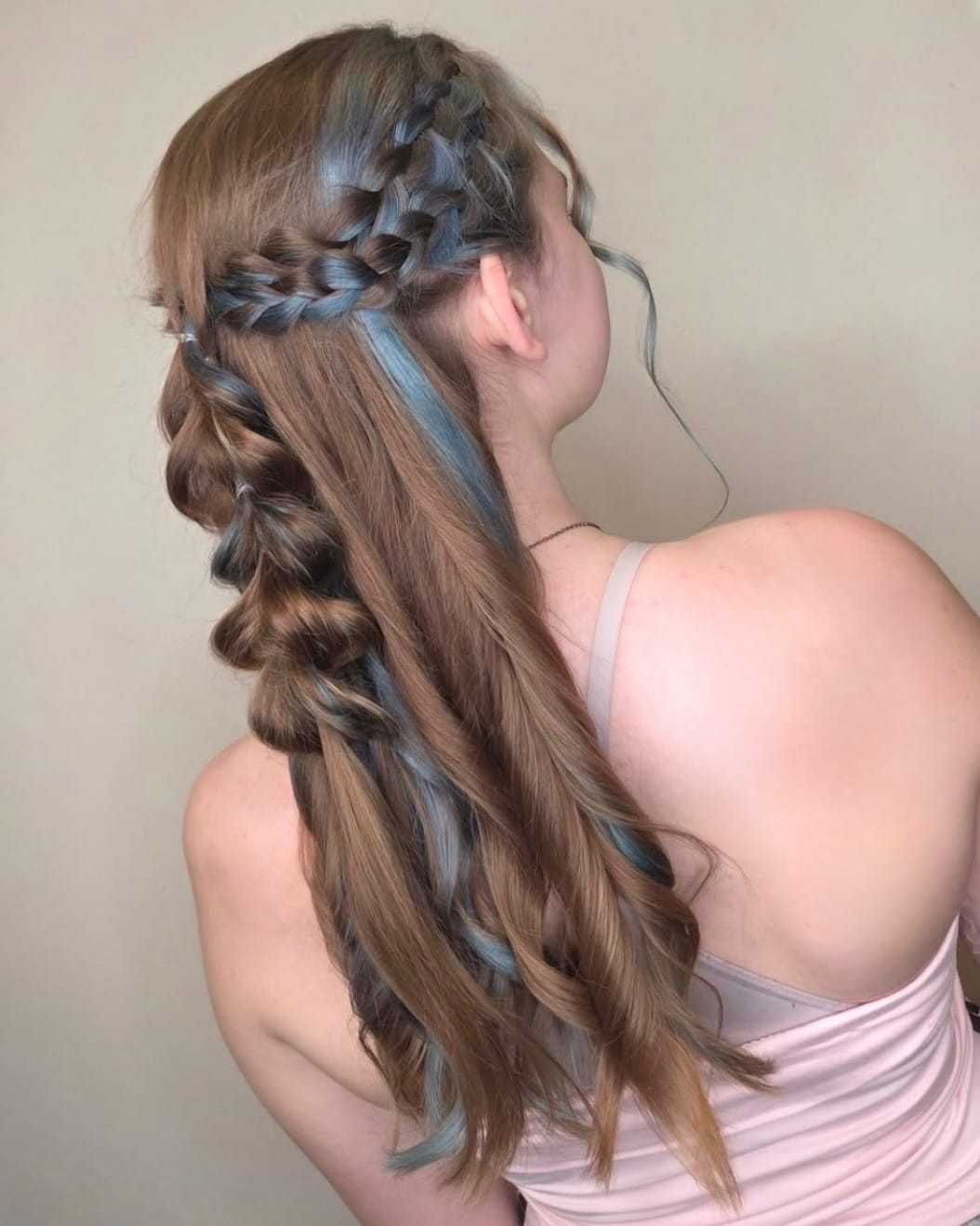 Braided hairstyle with blue highlights on a woman wearing a pink top, viewed from the back.