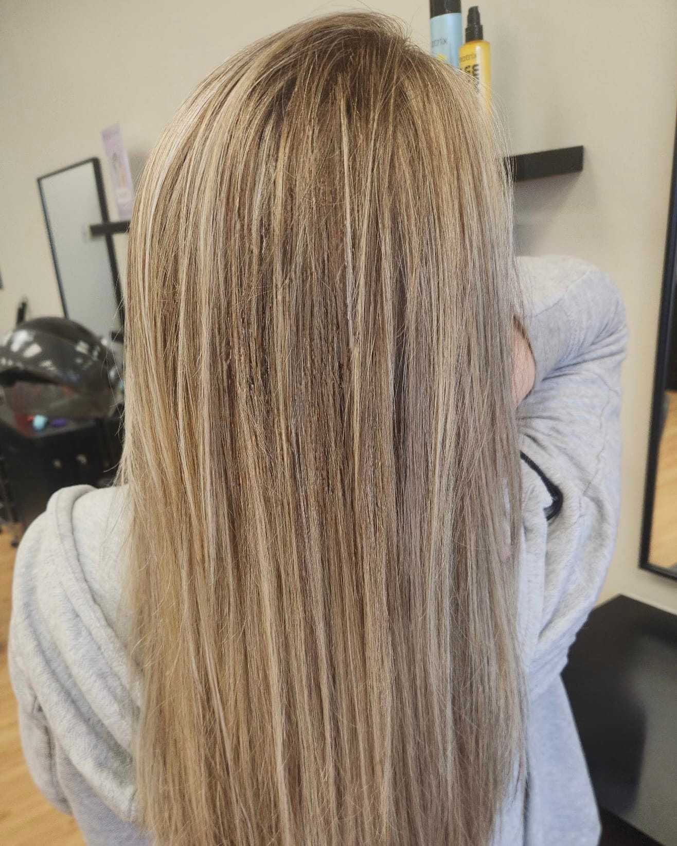 Blonde hair with highlights styled straight in a salon setting.