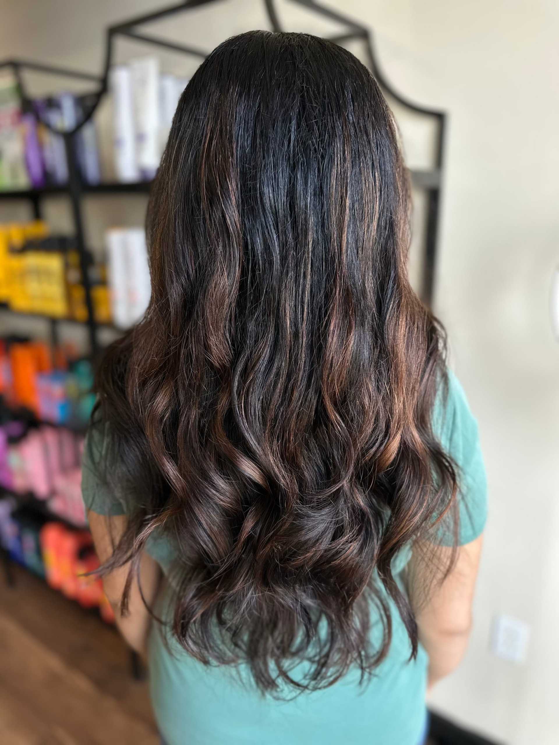 Long wavy brown hair with subtle highlights in a salon setting.