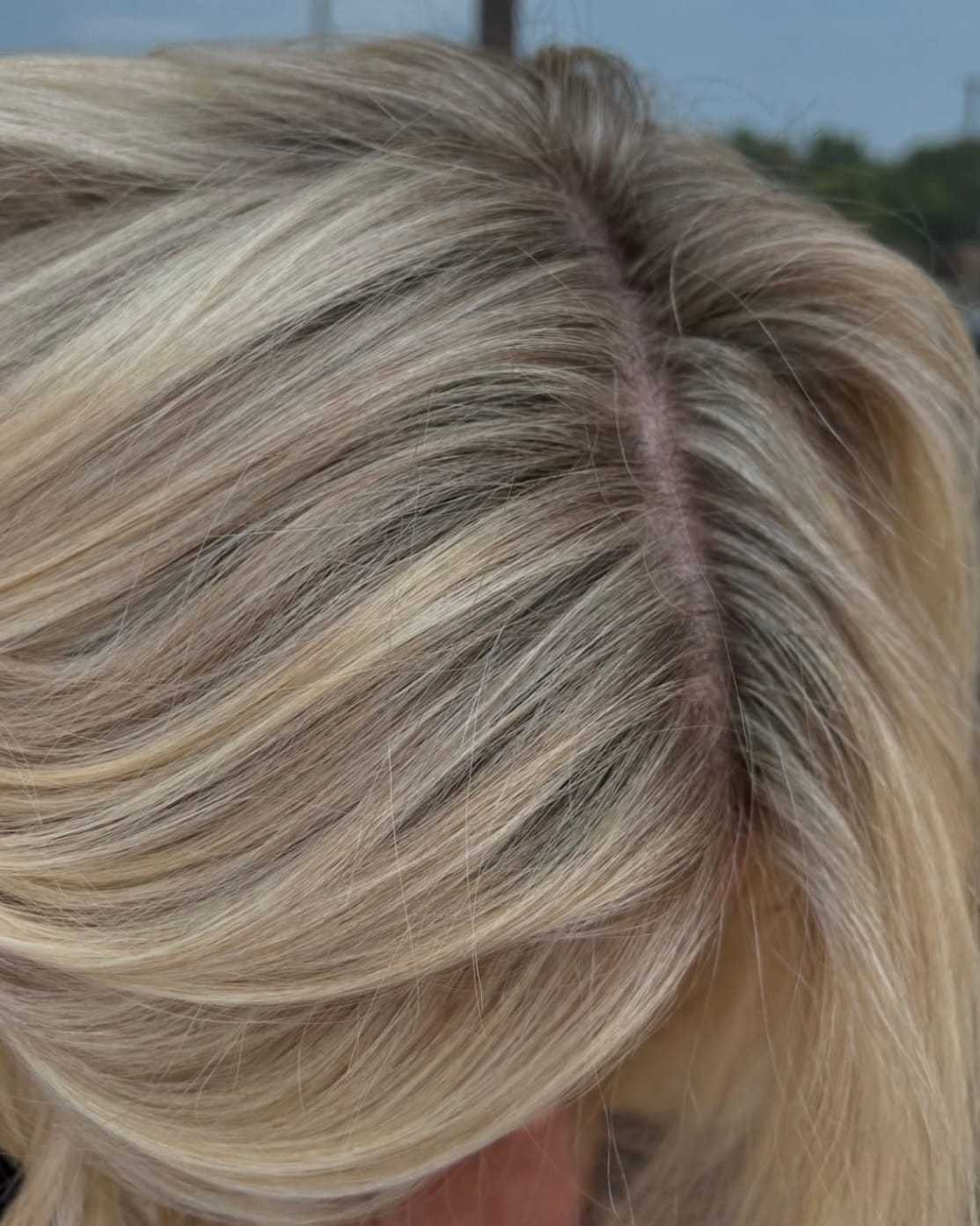 Blonde hair with visible roots and highlights under natural light.