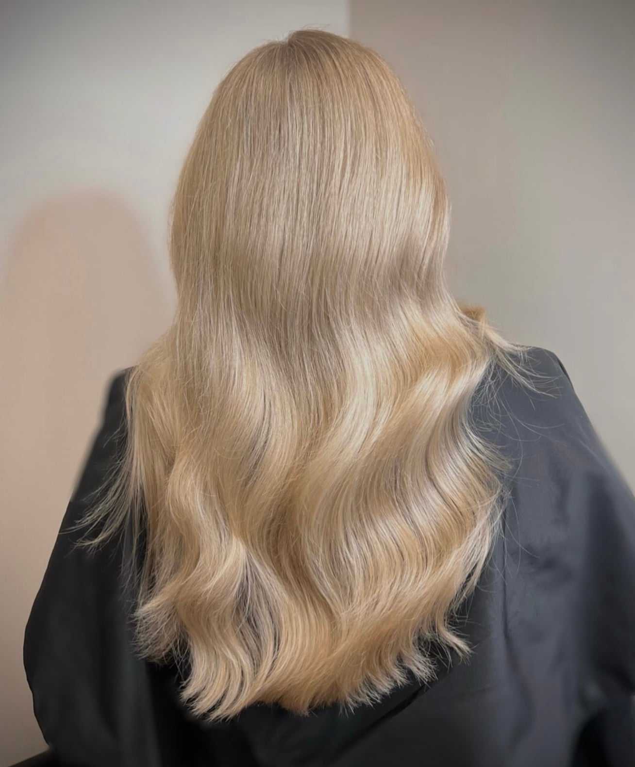 Long, wavy blonde hair cascading down a person's back, styled sleekly and elegantly.