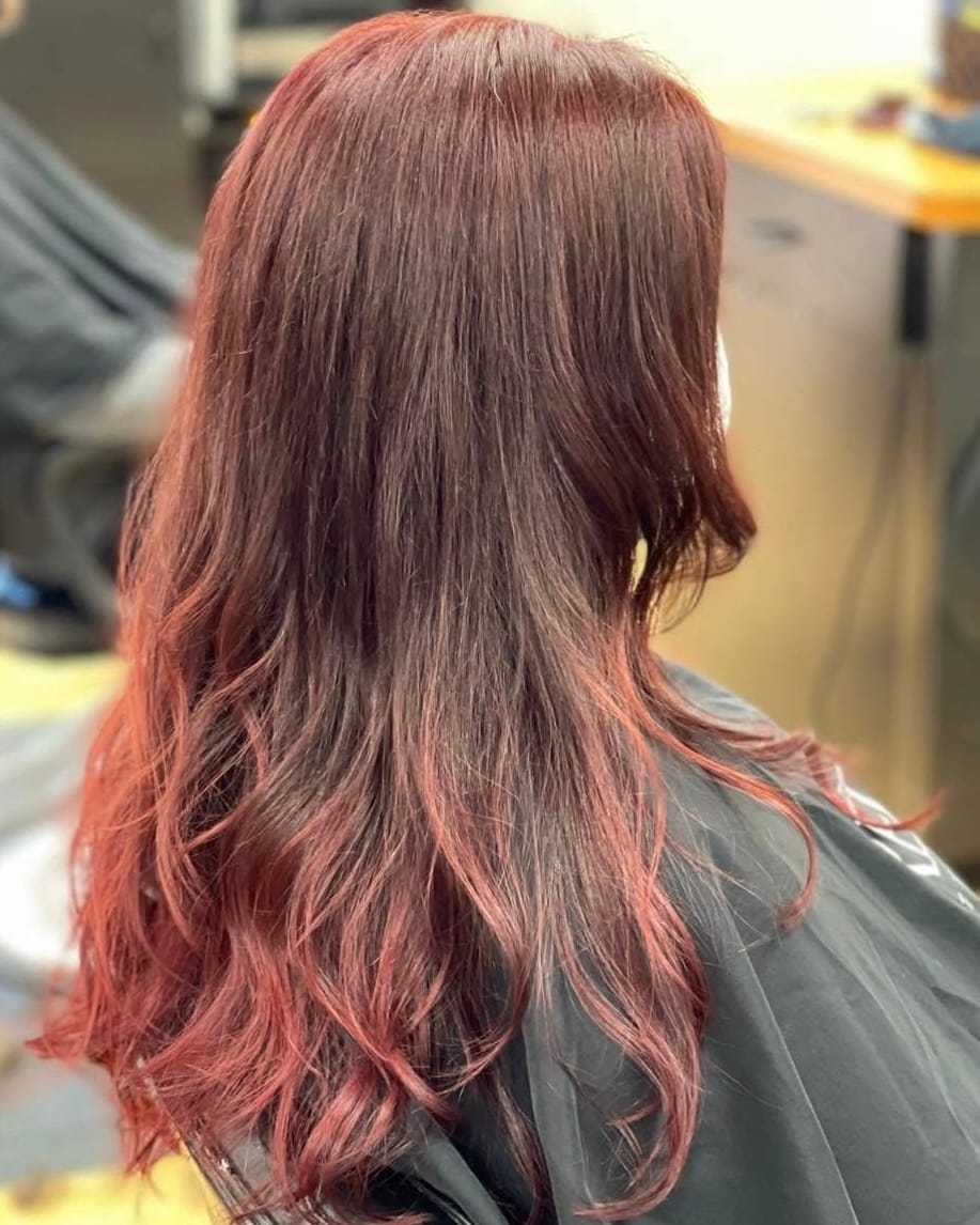 Red hair with soft curls and a glossy finish, styled in a salon chair.