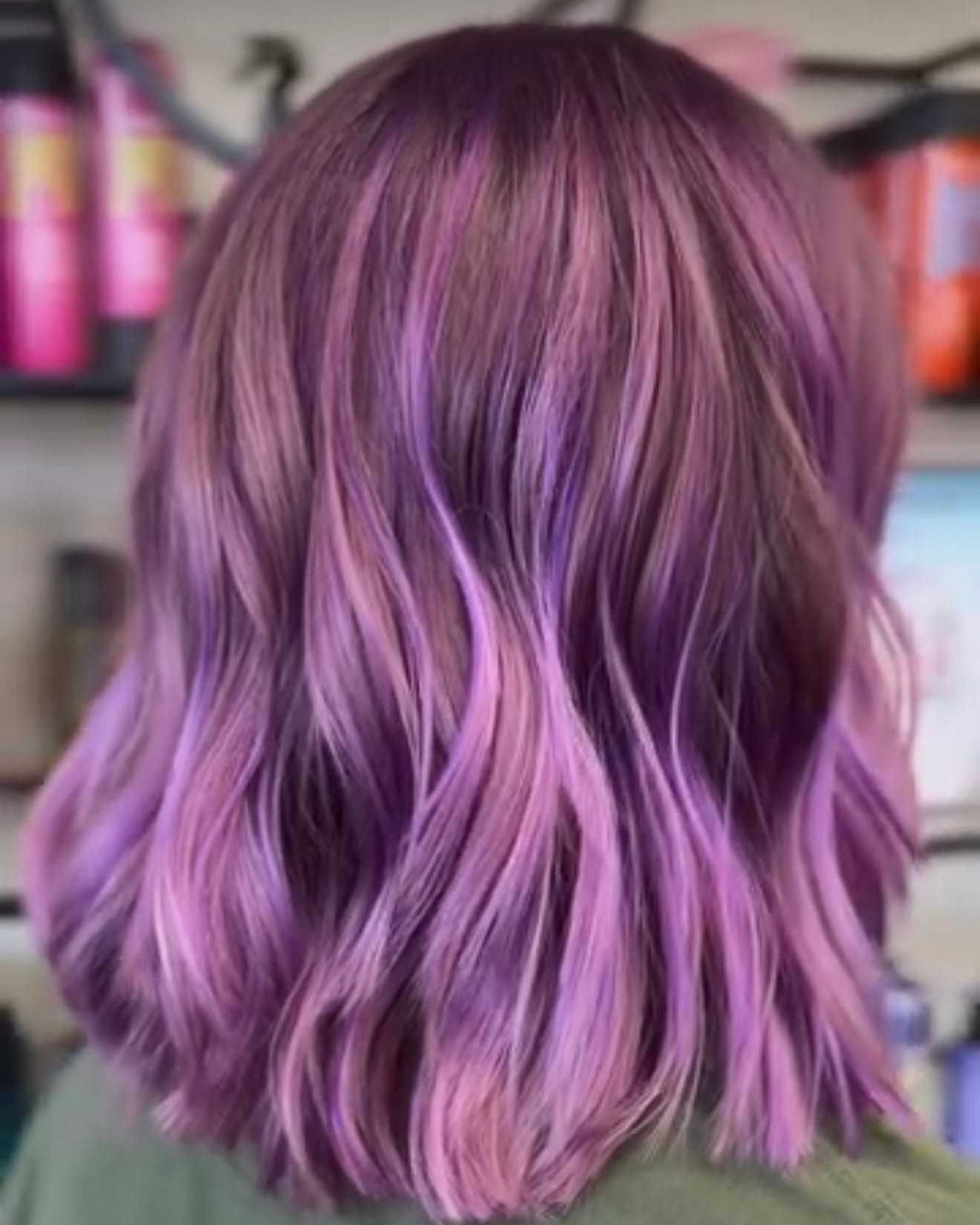 Purple ombre hair with waves against a salon background.
