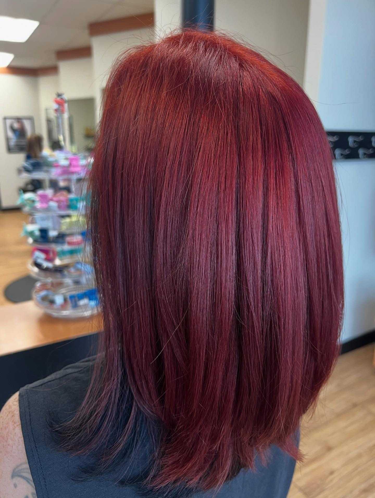 Woman with vibrant red hair in a salon setting.
