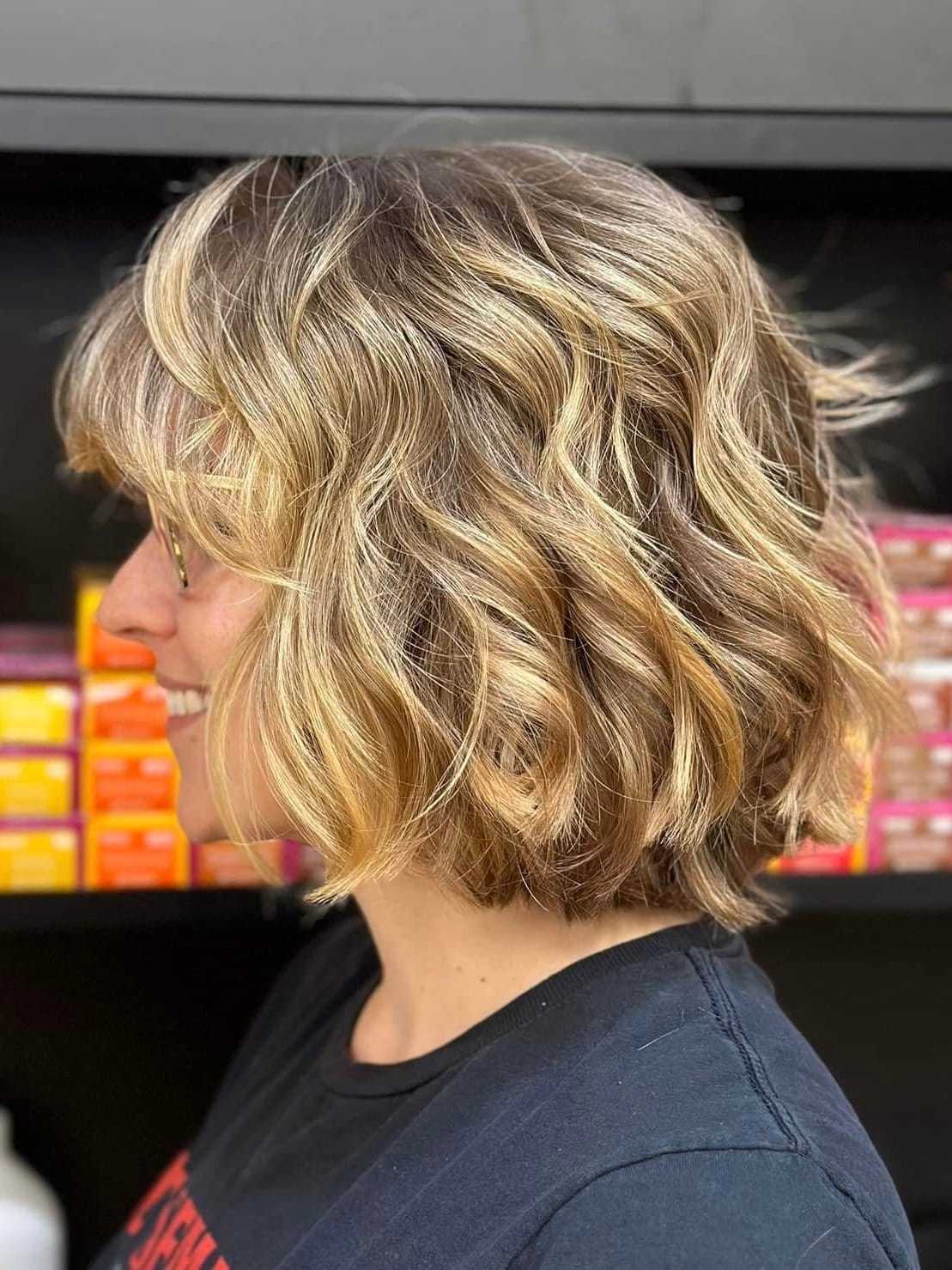 Short blonde wavy bob hairstyle on woman in profile view.