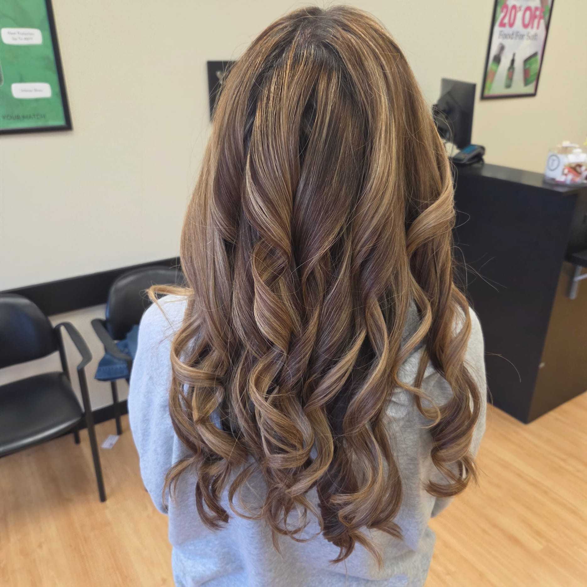 Long curled hair after salon styling, with soft highlights.