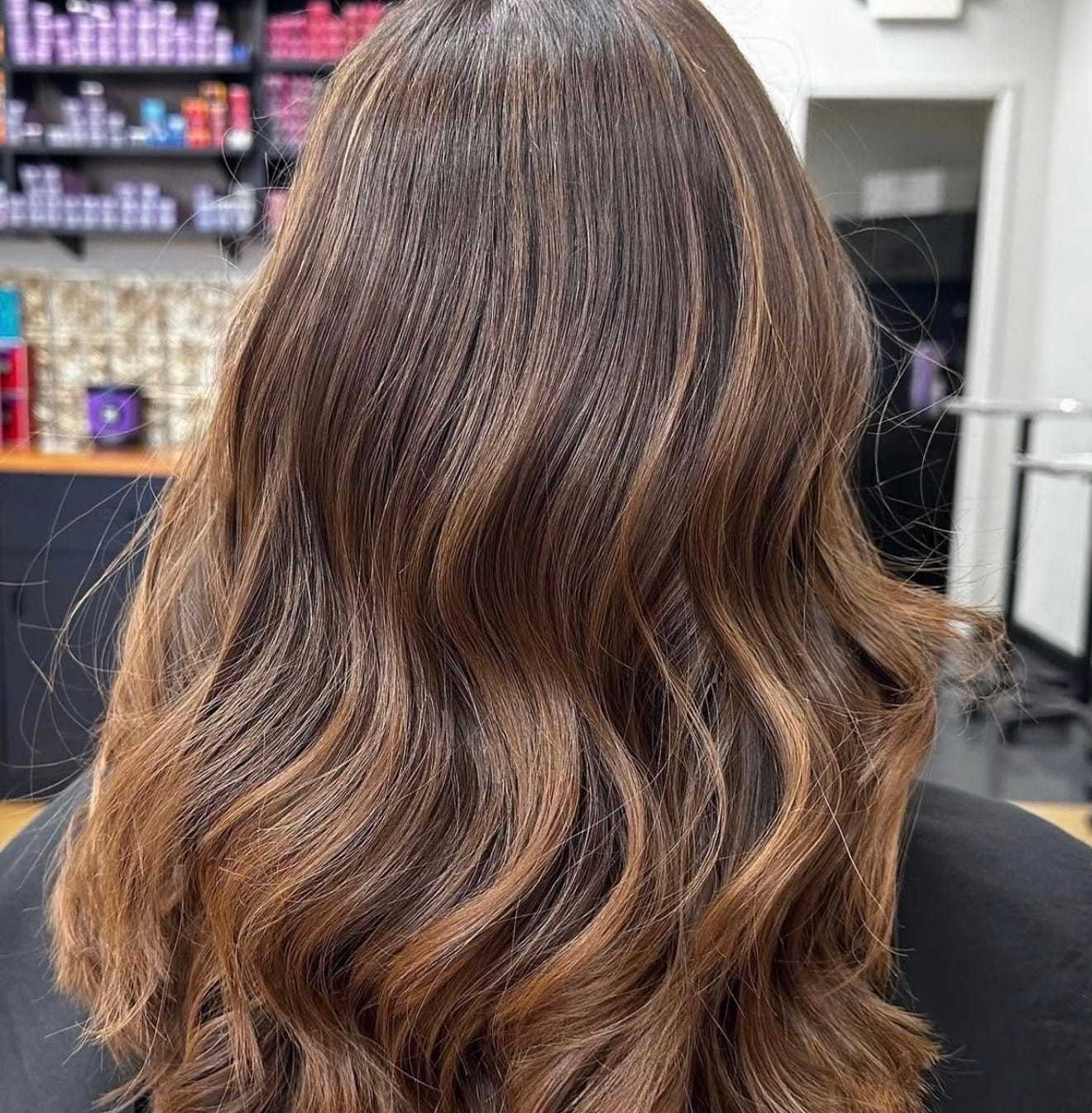 Wavy brown hair with highlights in a salon setting.