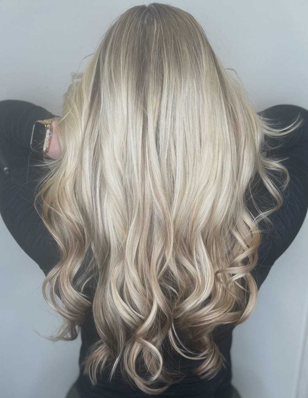 Blonde woman with long, wavy hair styled elegantly from the back.