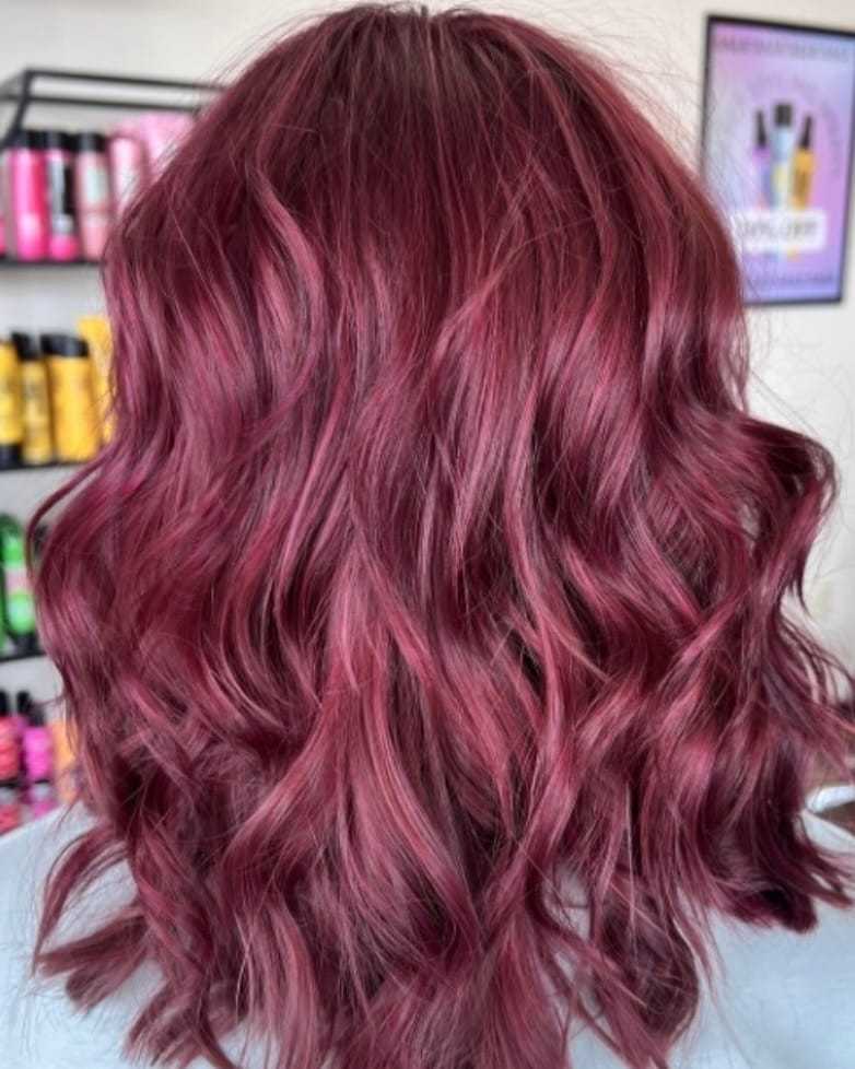 Wavy hair colored in rich burgundy, with hair products visible in the background.