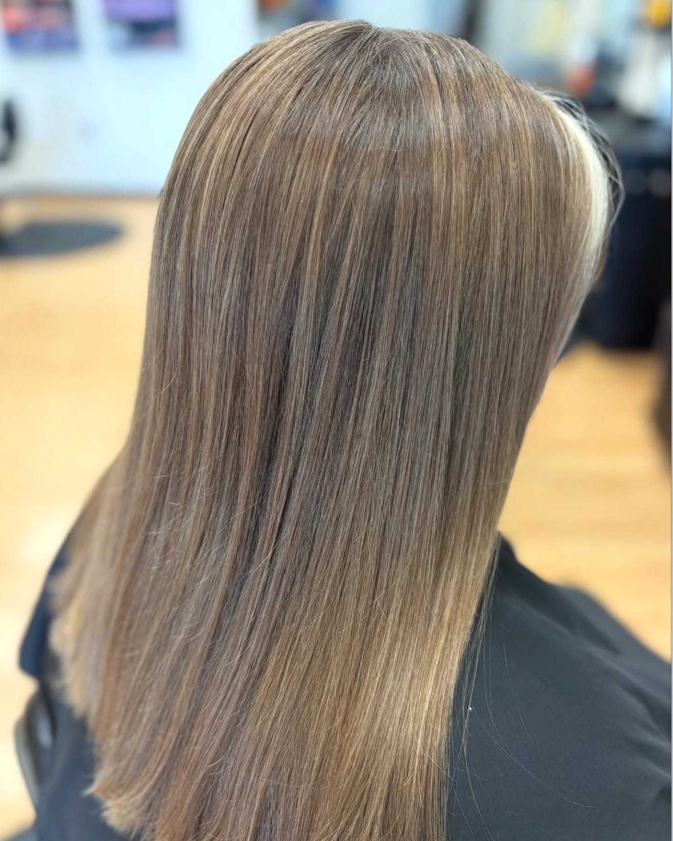Straight, layered hair with subtle highlights in a salon setting.
