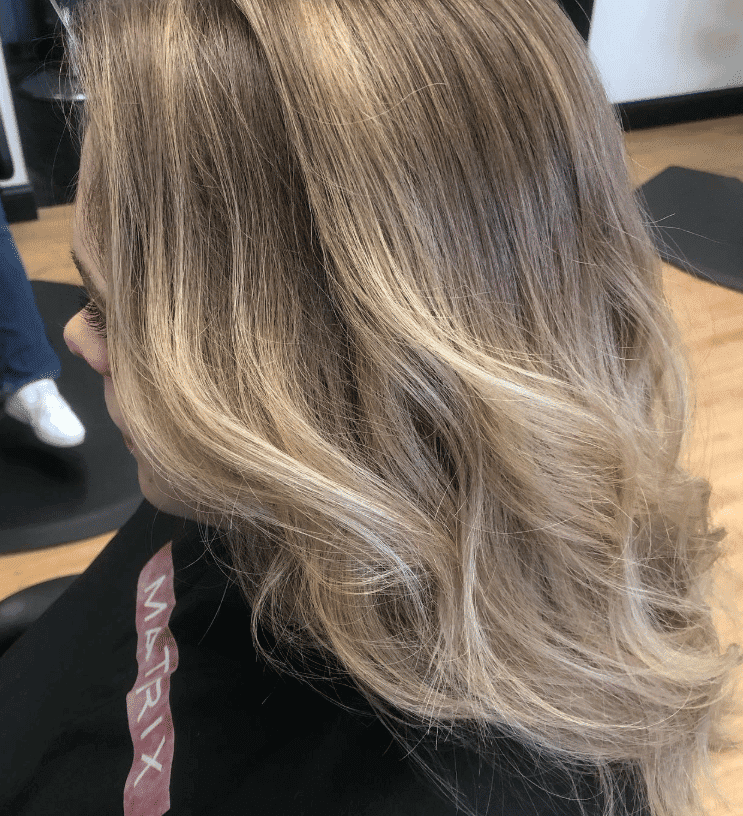 Blonde hair with soft waves and subtle highlights, styled in a salon setting.
