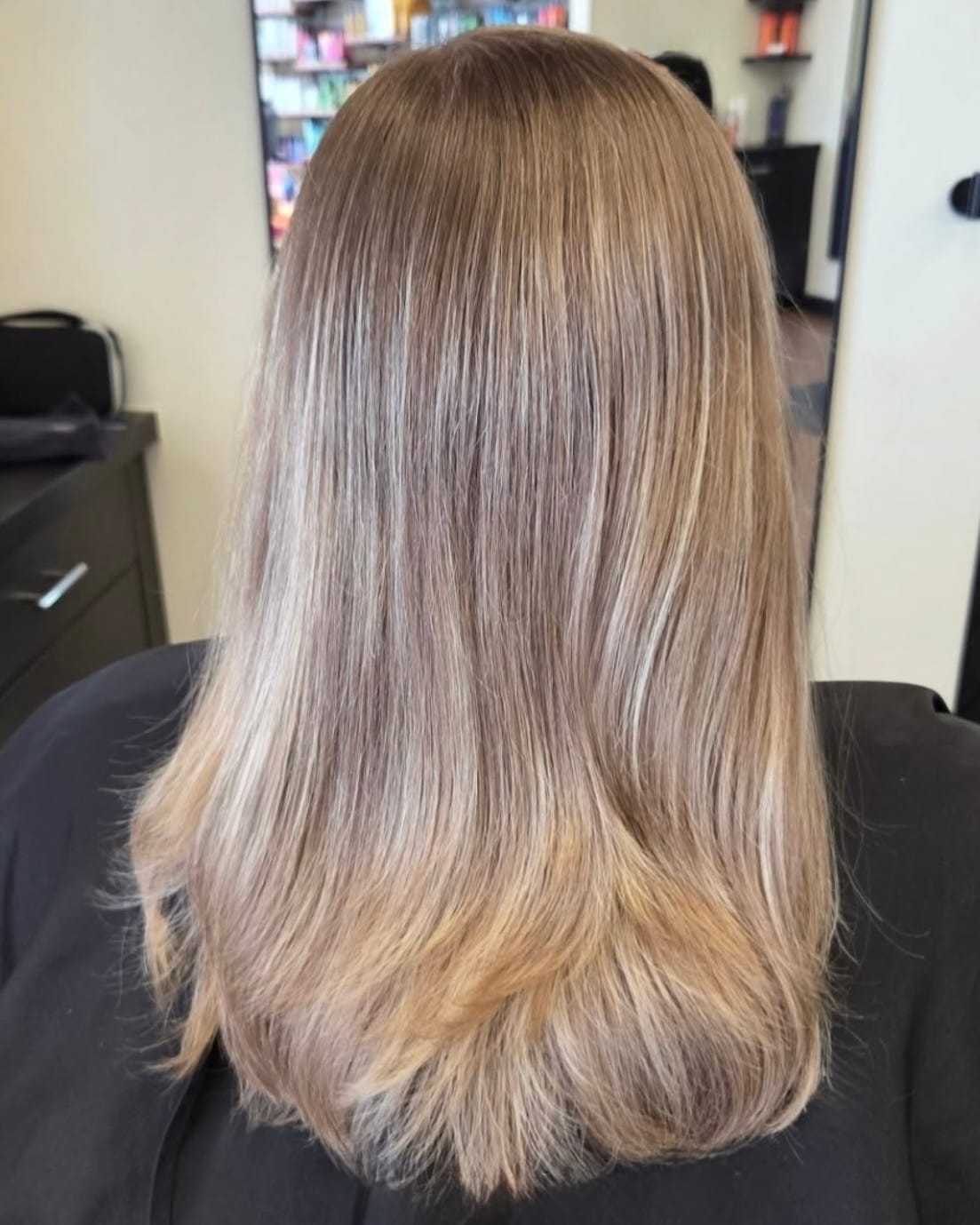 A woman with smooth, layered blonde hair in a salon setting.