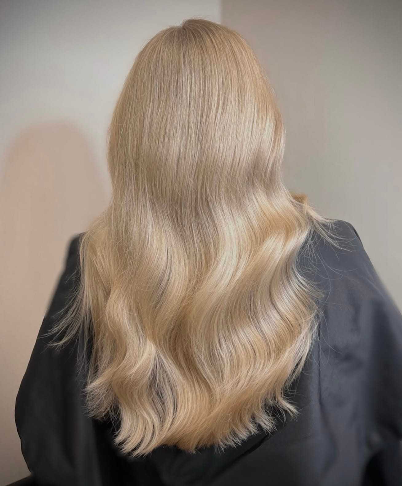Long, wavy blonde hair cascading down a person's back, styled sleekly and elegantly.