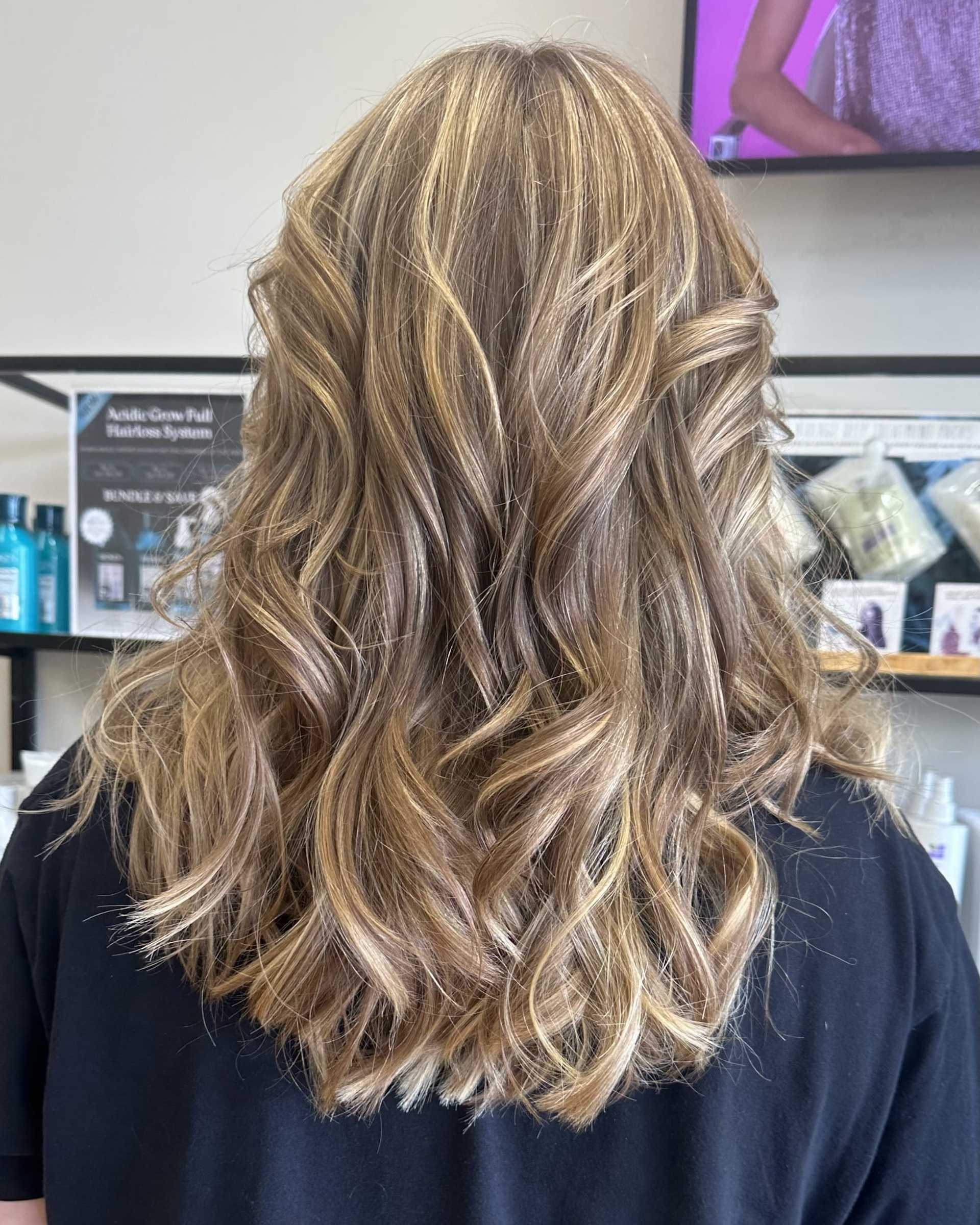 Wavy blonde hair with highlights in a salon setting.