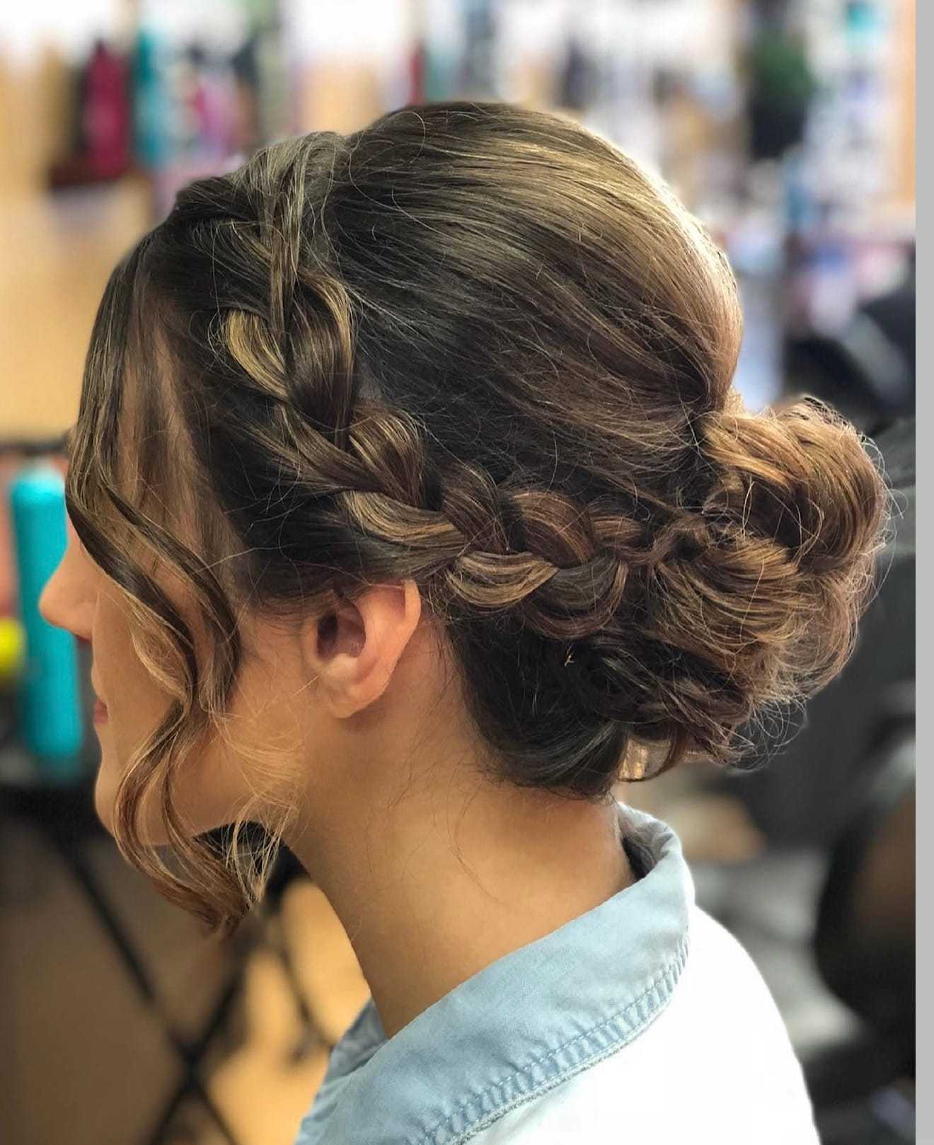 Braided updo hairstyle with loose curls in a salon setting.