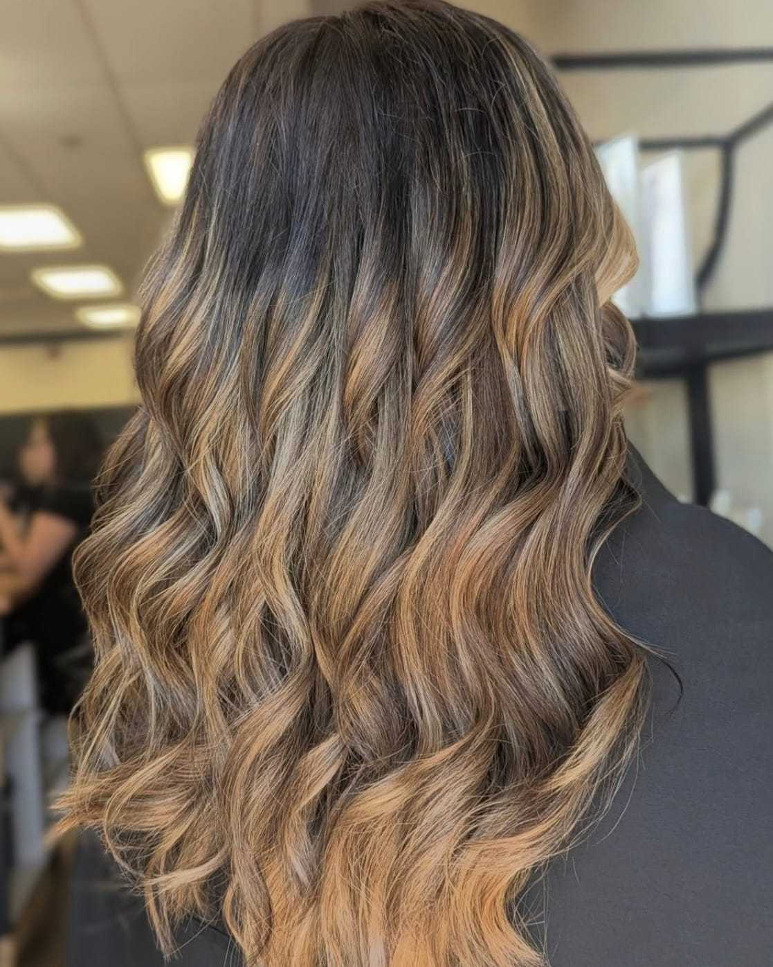Wavy, shoulder-length hair with caramel and dark brown highlights.