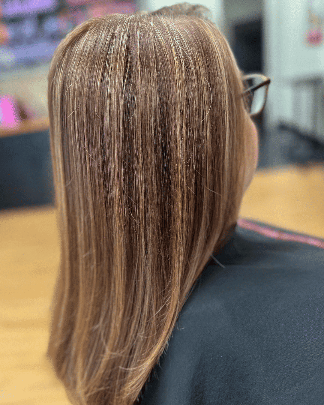 Long, straight, highlighted hair viewed from the back in a salon setting.