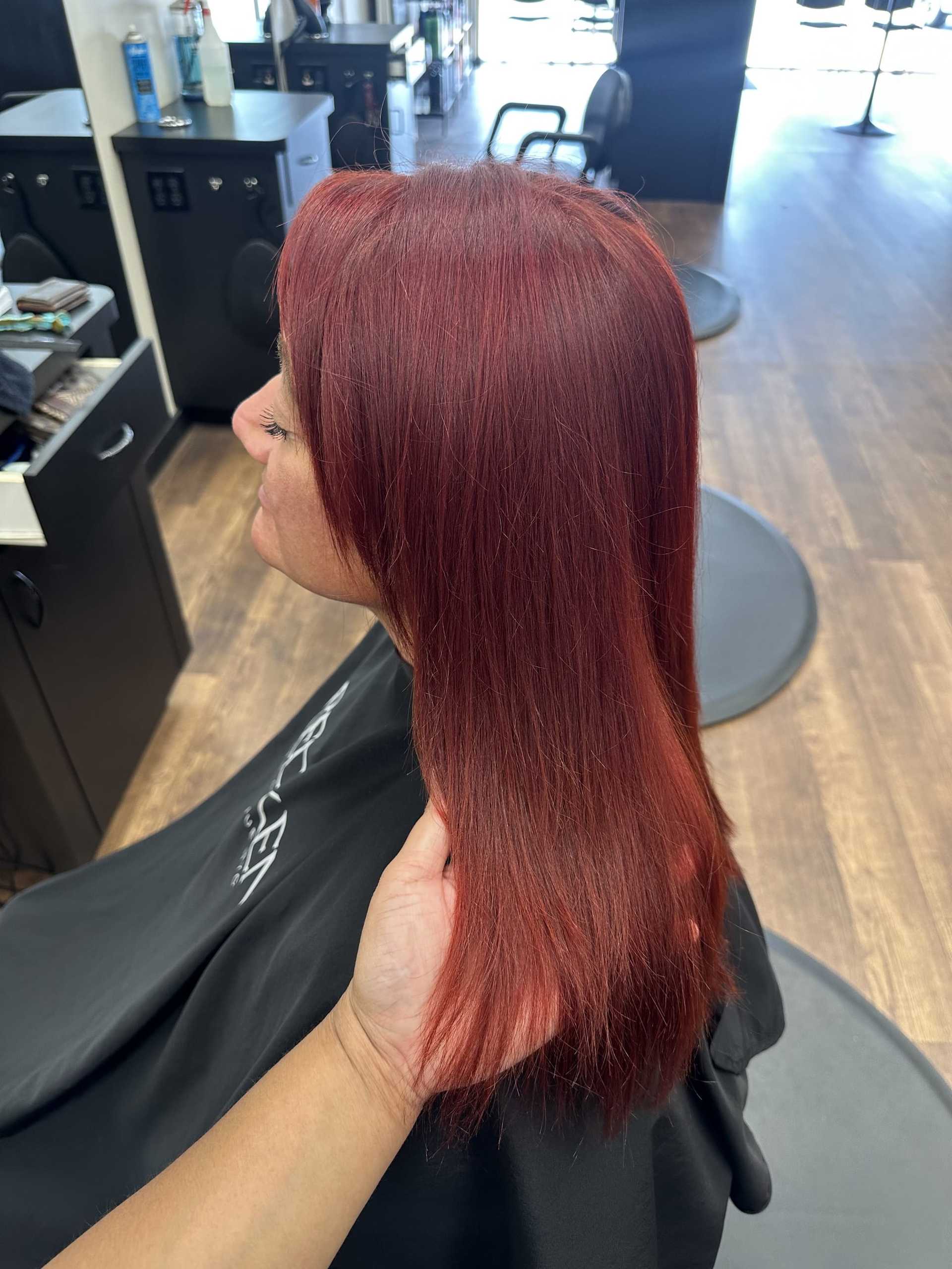 Red-haired woman getting a haircut at a salon. Stylist adjusting hair.