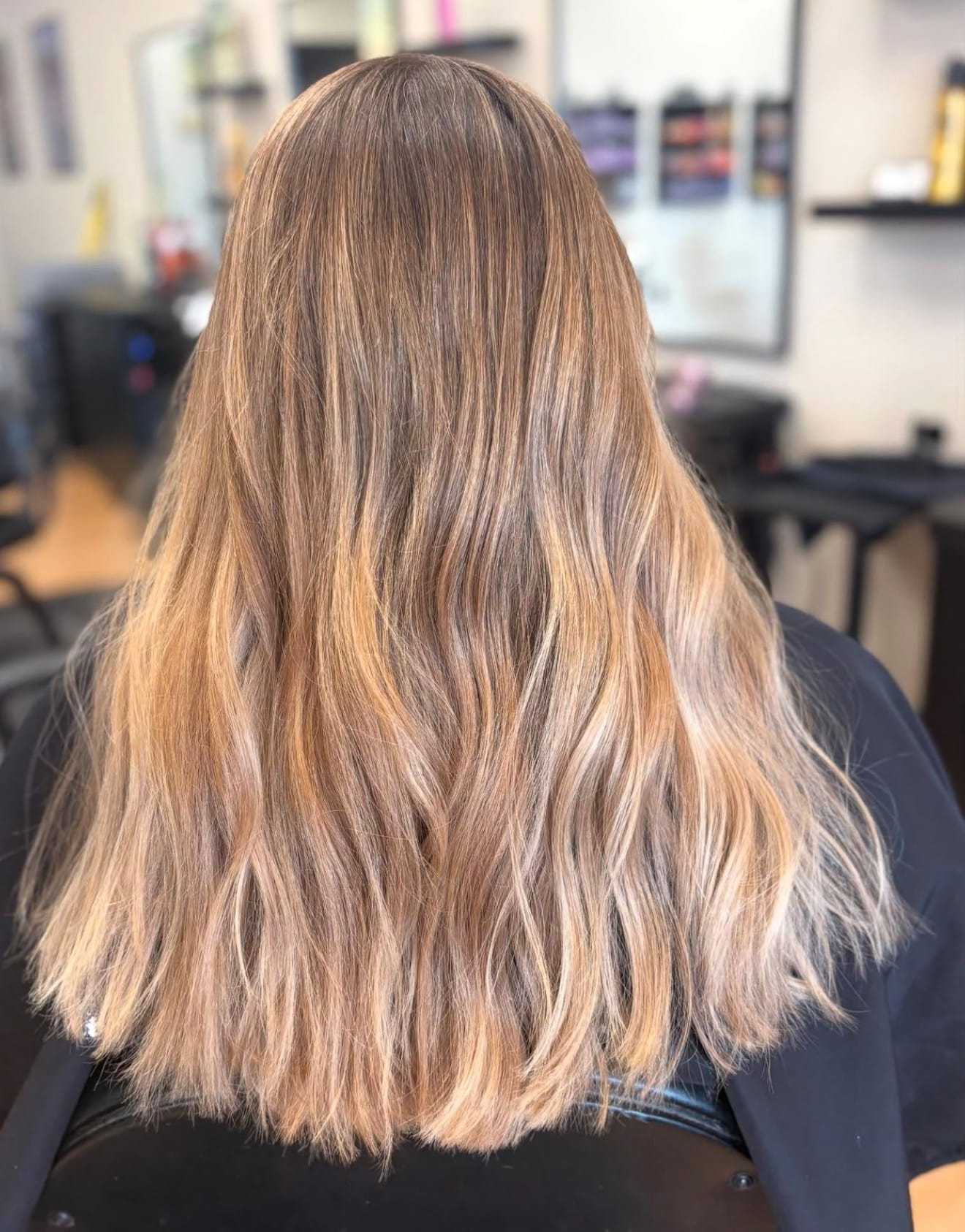Wavy blonde hair with highlights in a salon setting.