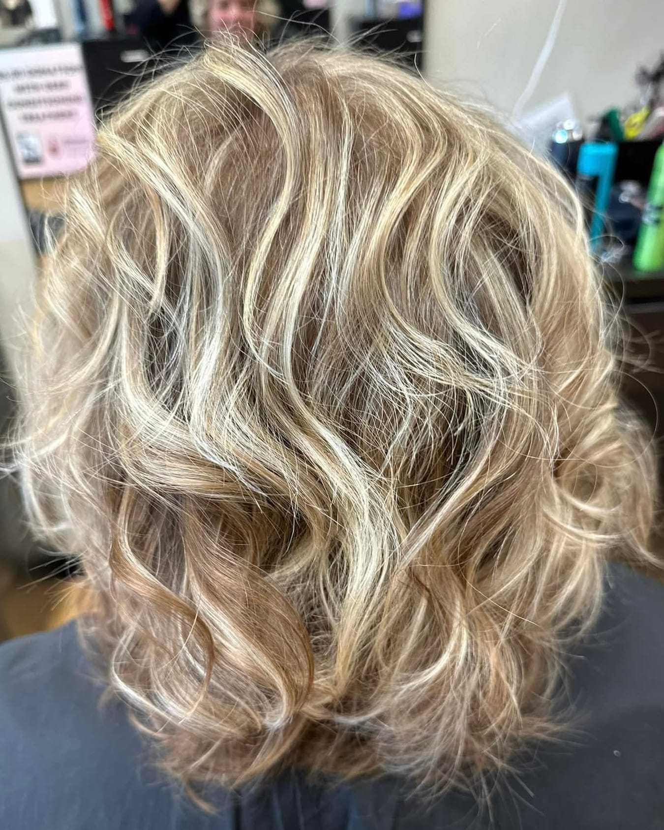 Wavy blonde hair with highlights in a salon setting.