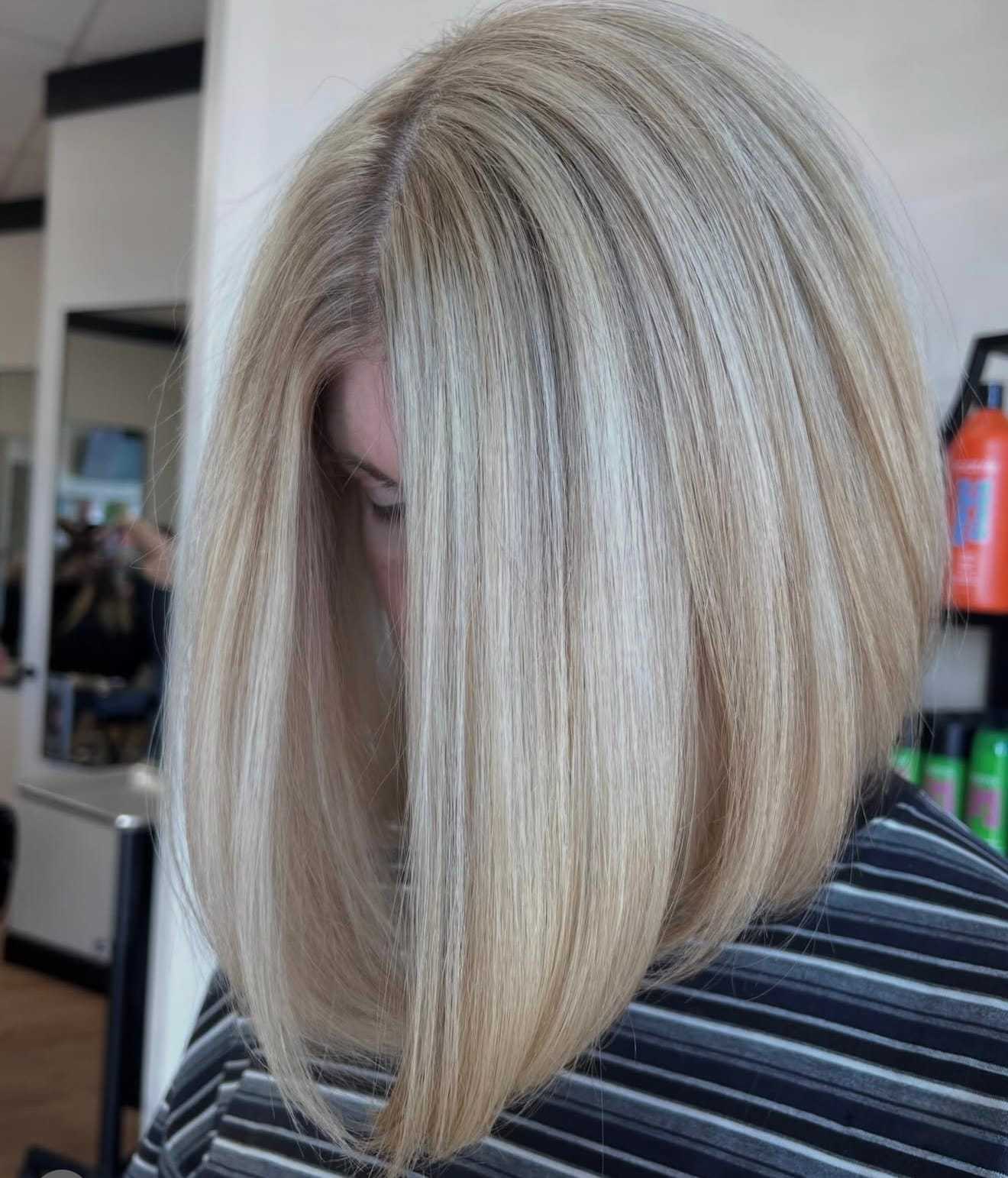 Short blonde bob haircut with smooth, straight strands in a salon setting.