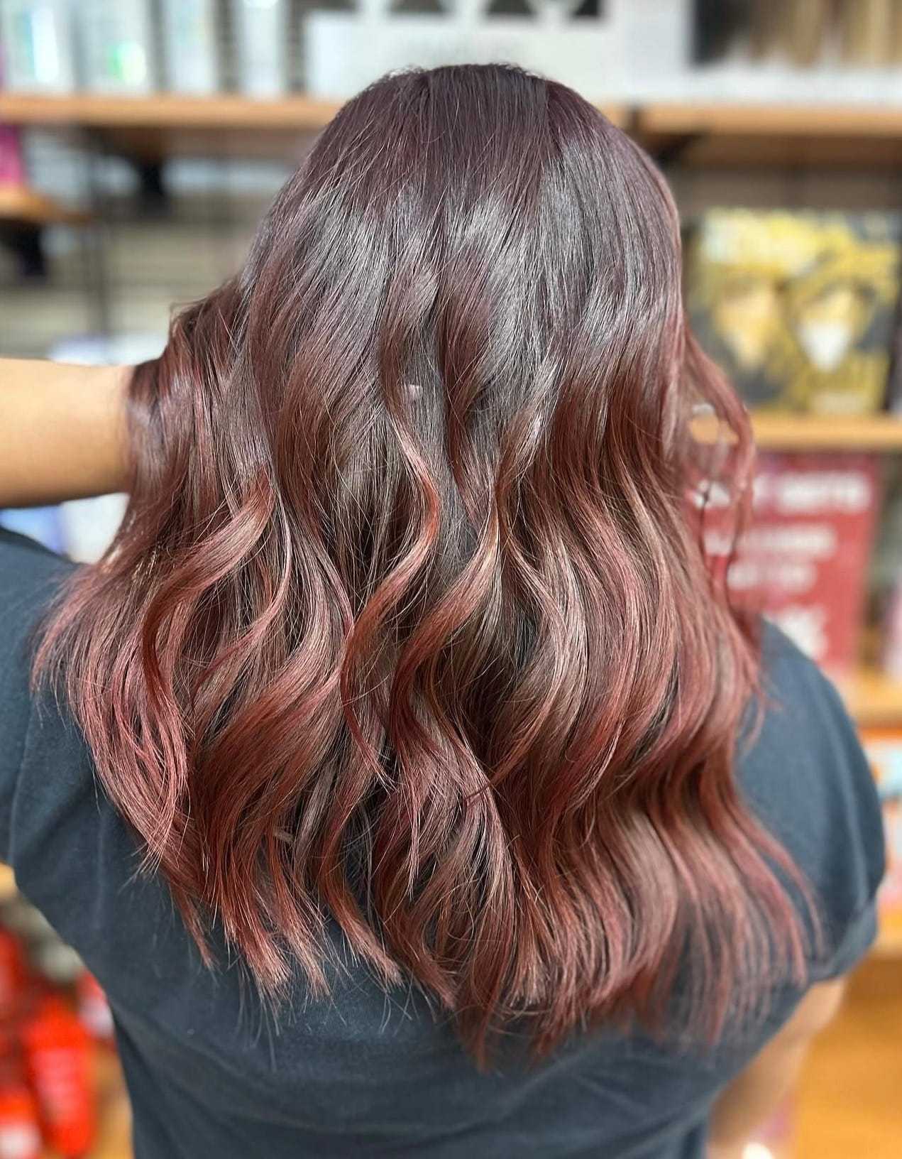 Wavy hair with shades of brown and red, styled in loose curls.