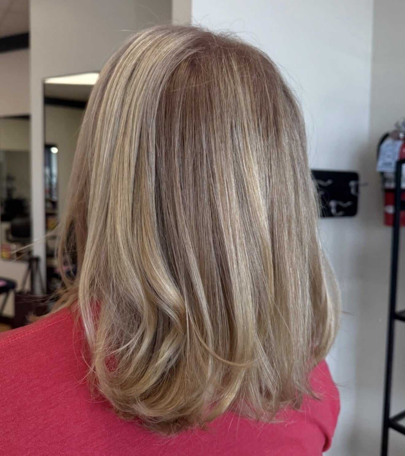 Blonde hair with highlights shown from the back in a salon setting.
