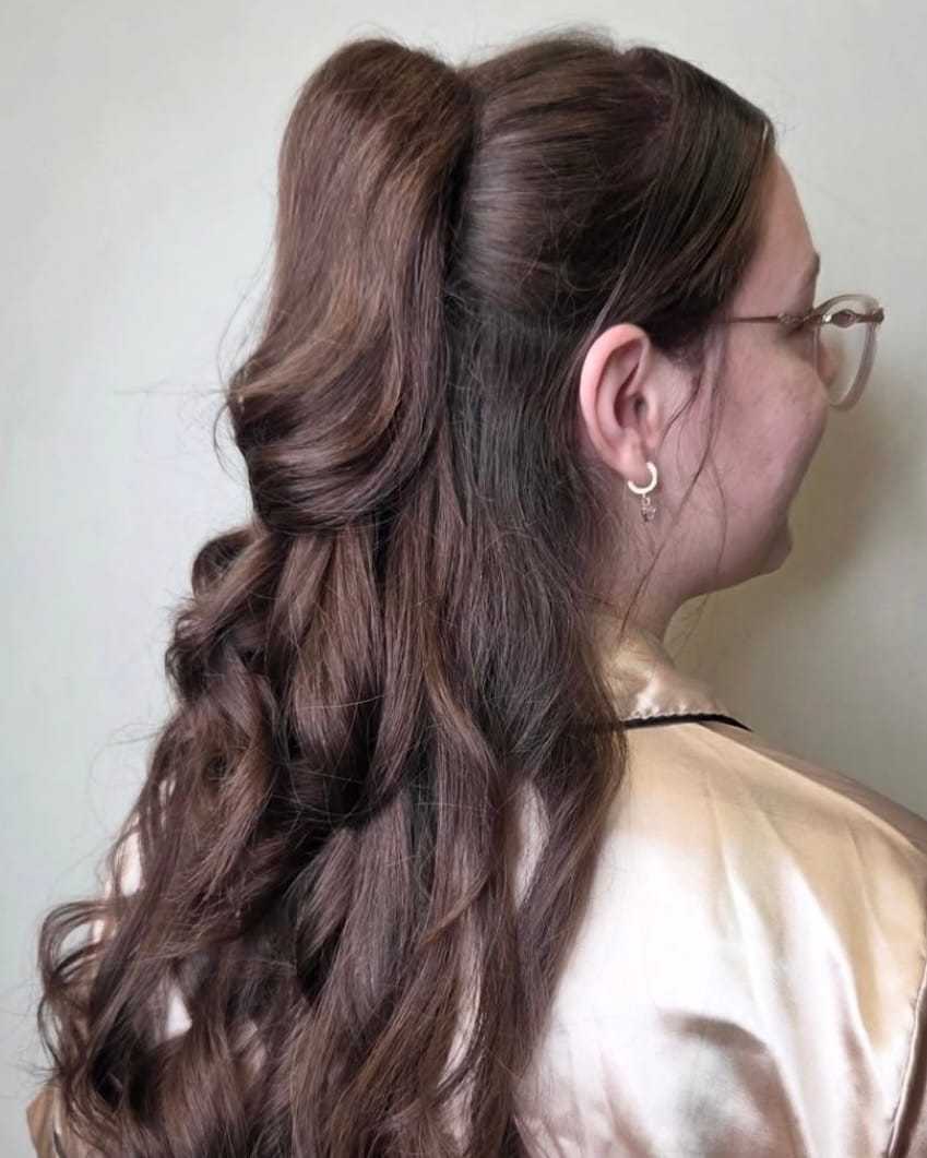 Long curly brown hair styled in a half-up ponytail on a woman with glasses.
