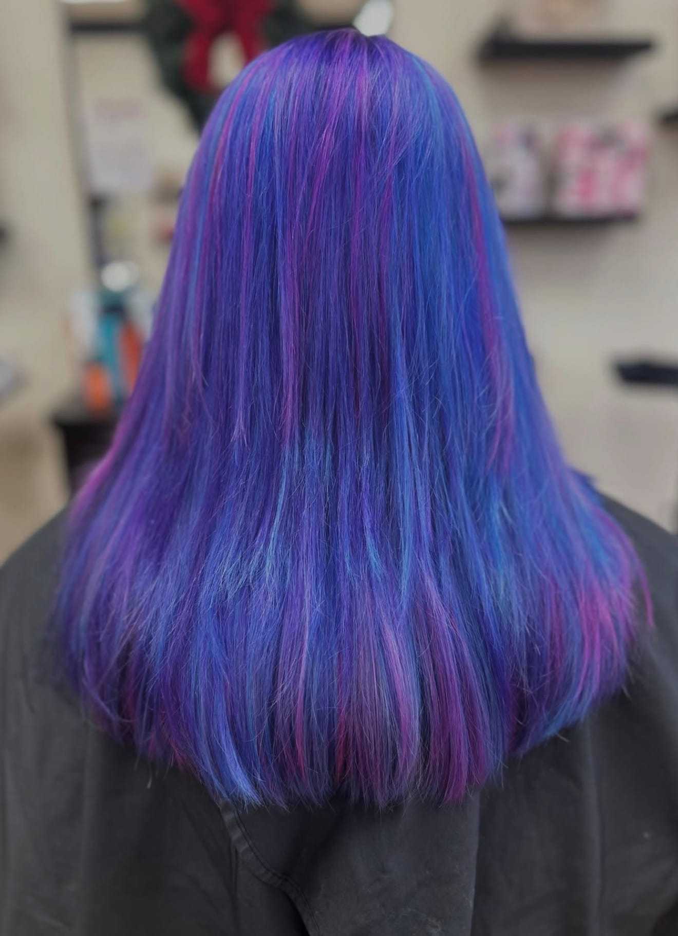 Blue and purple long hair viewed from the back inside a salon.