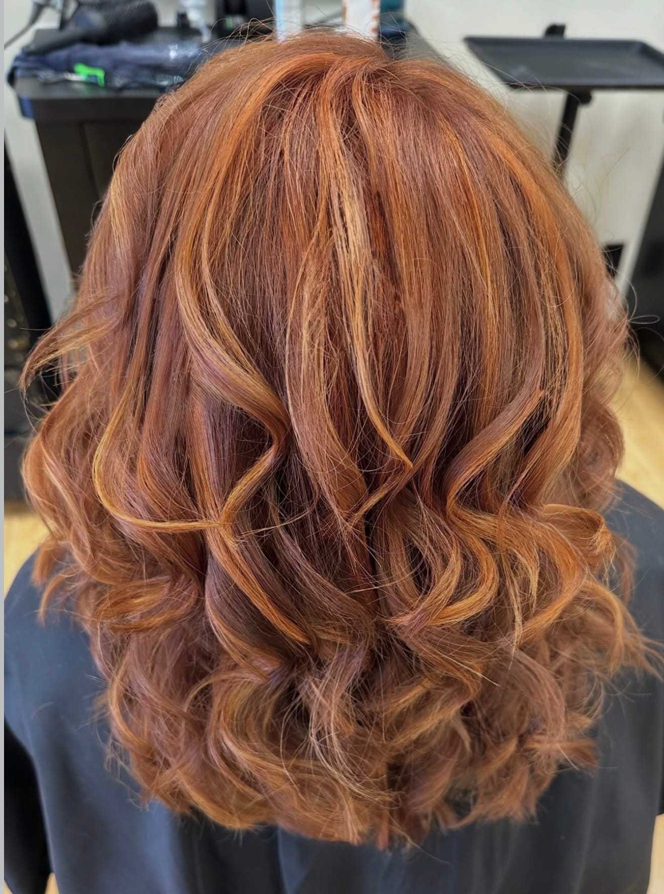 Curly red hair styled in loose waves at a salon.