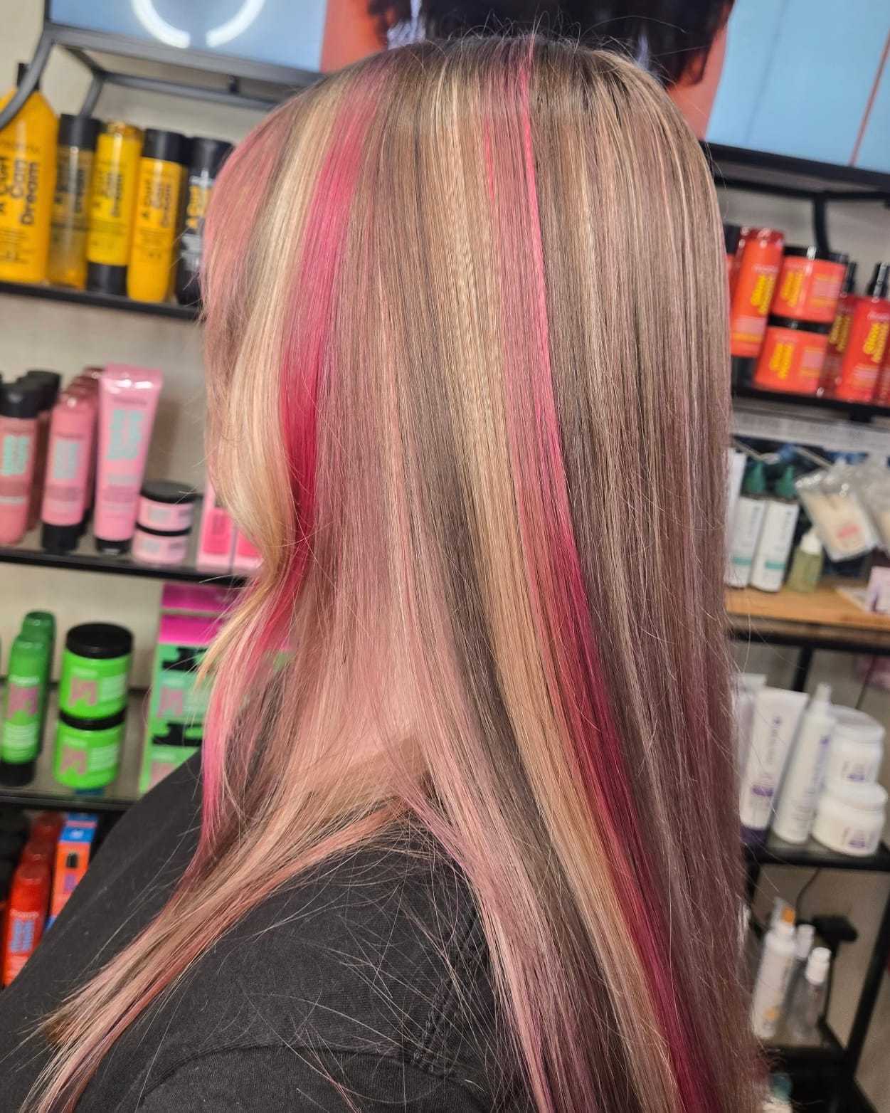 Hair with pink, blonde, and brown highlights in a salon setting.