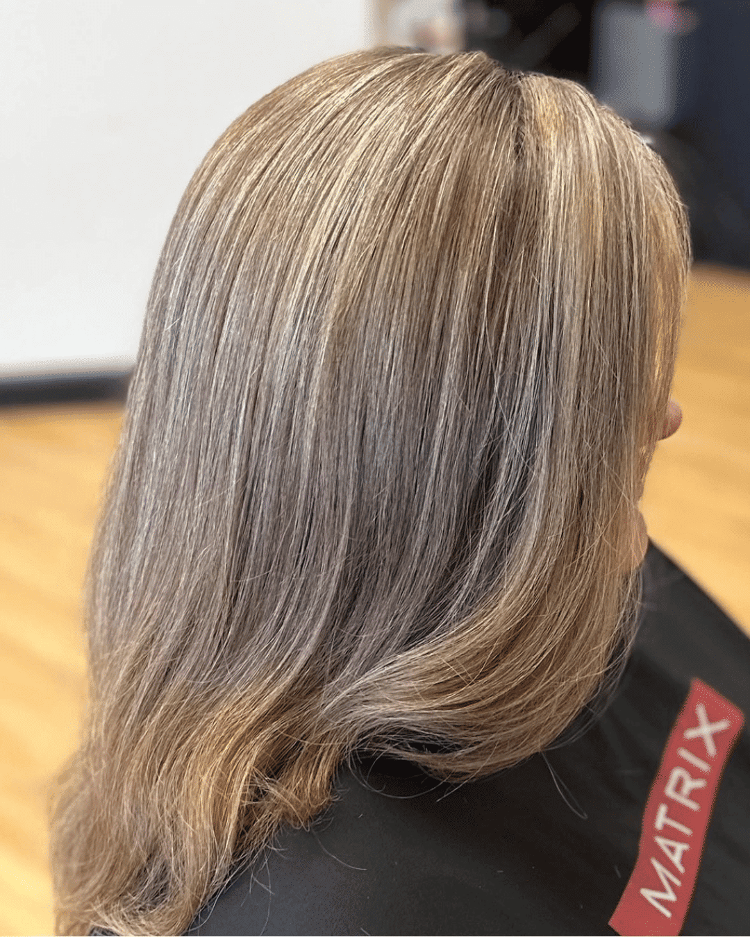 Hair with blonde highlights styled in a salon, Matrix branding visible on cape.