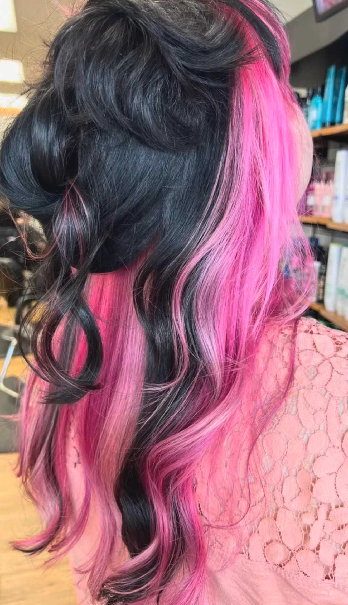 Hair styled with black and vivid pink curls in a salon setting.