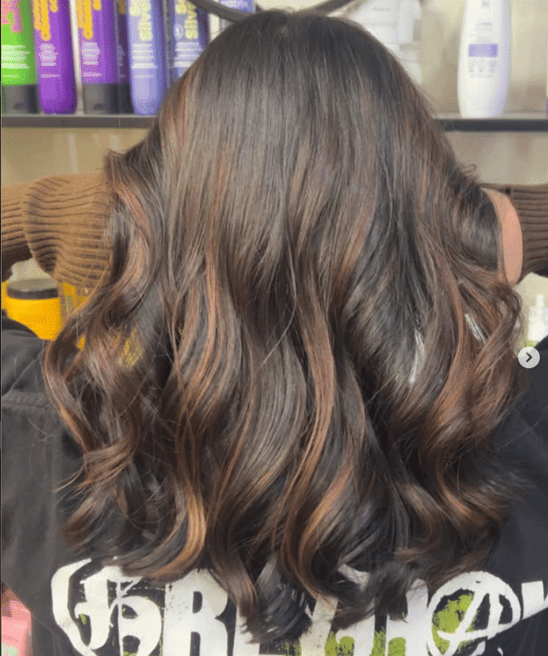 Stylish brown hair with soft curls in a salon setting.