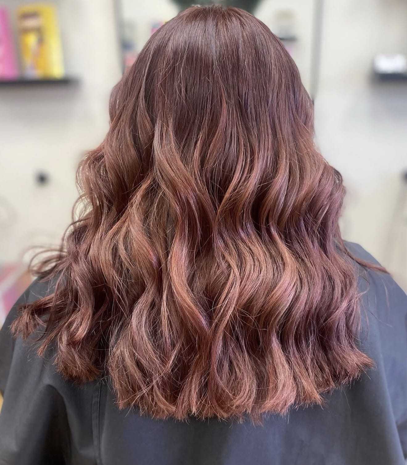 Wavy, shoulder-length hair with soft brown highlights styled in loose curls.