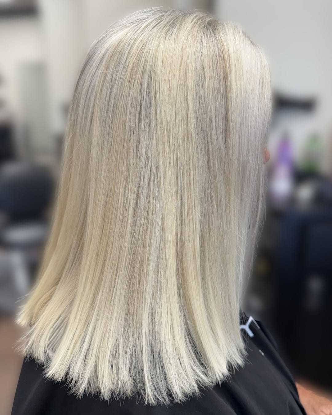 Short, smooth, platinum blonde hairstyle in a salon setting.
