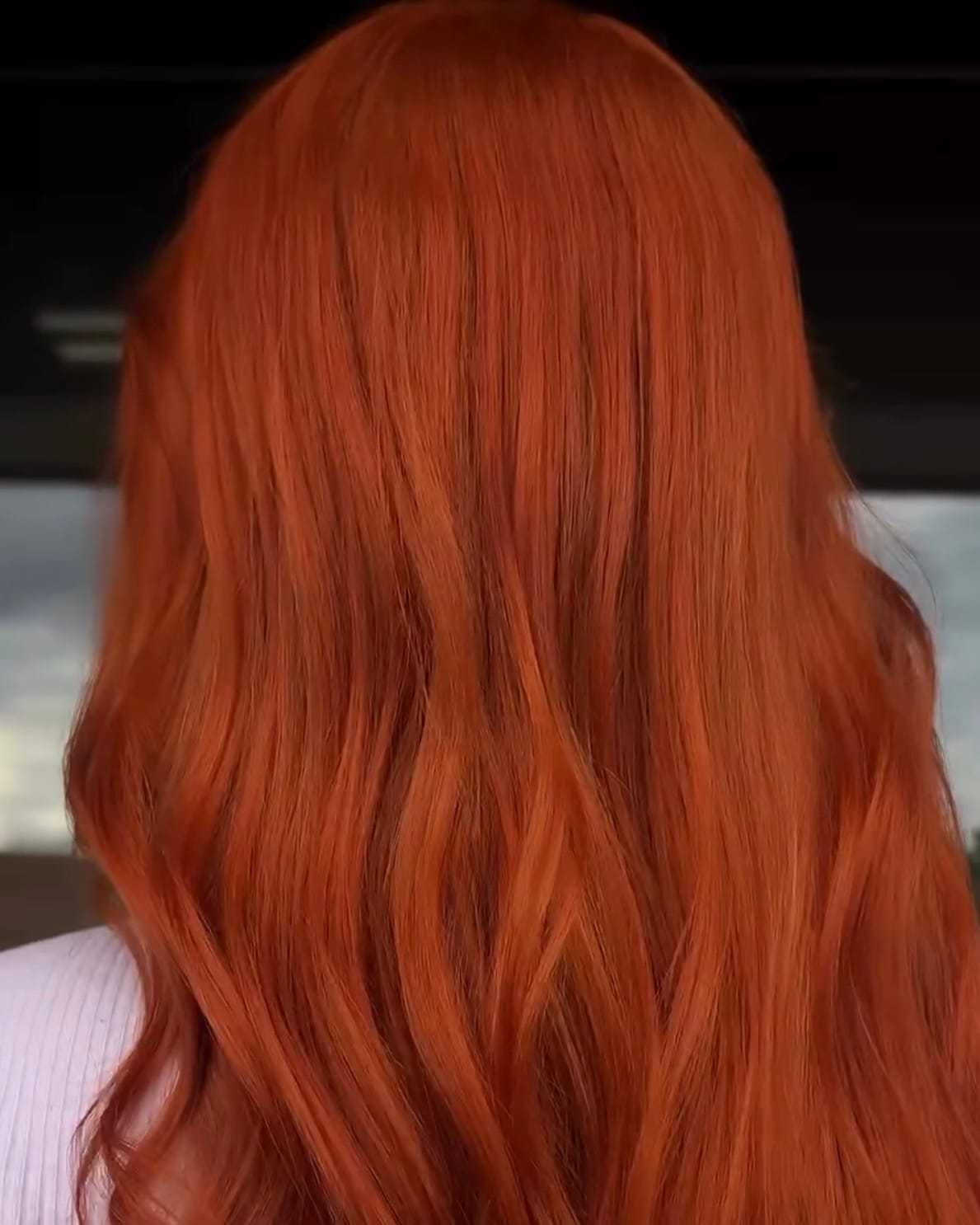 Wavy, vibrant red hair cascading down someone's back.