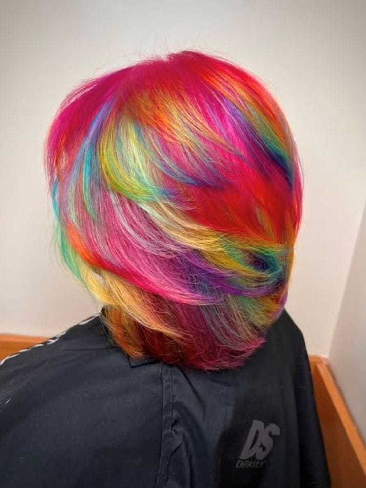 Multicolored rainbow hairstyle with vibrant pink, red, blue, and yellow hues.