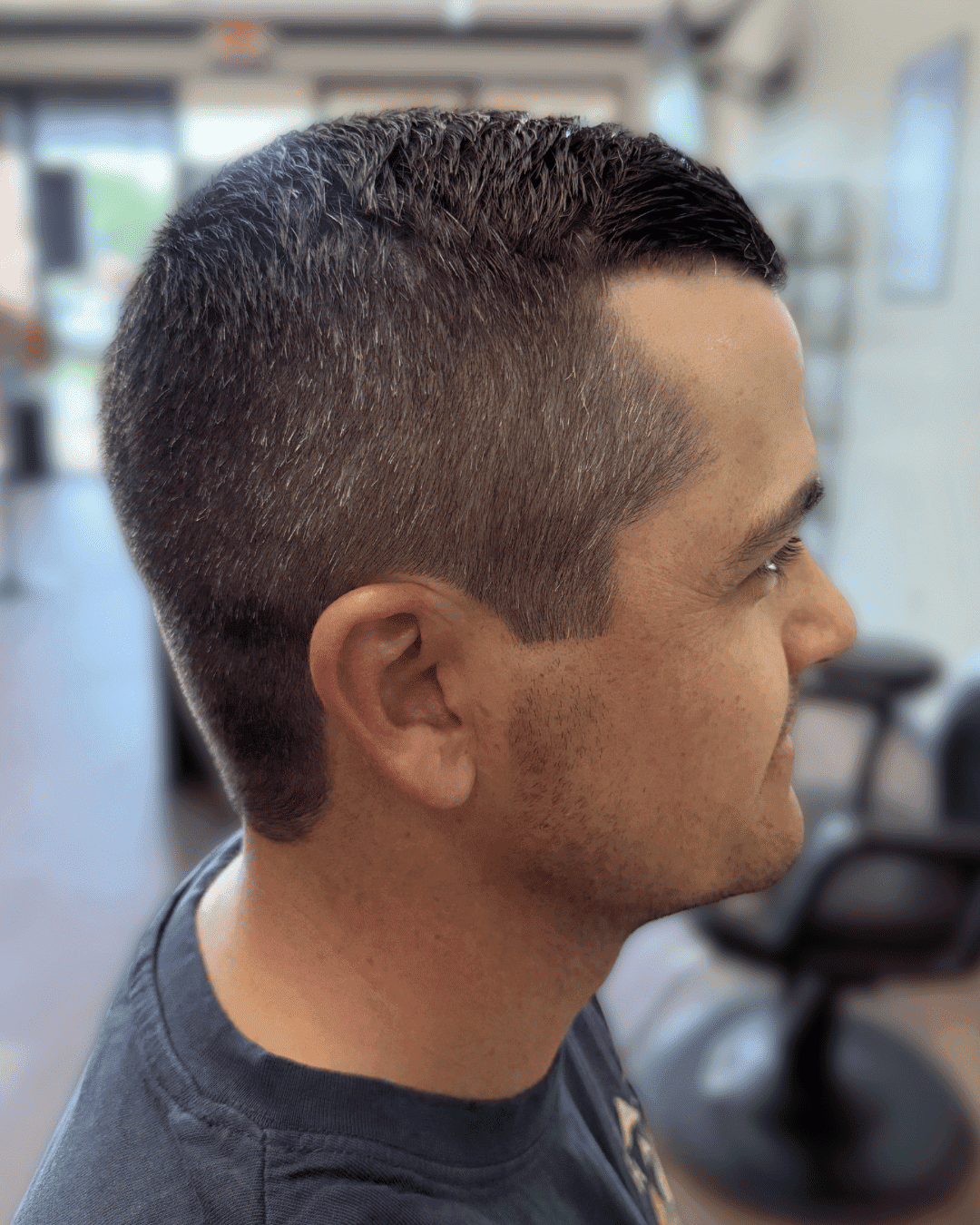 Man with a fresh haircut in a barbershop setting, viewed from the side.