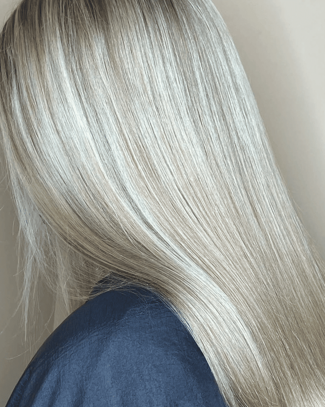 Smooth, shiny blonde hair against a neutral background, highlighting the silky texture.