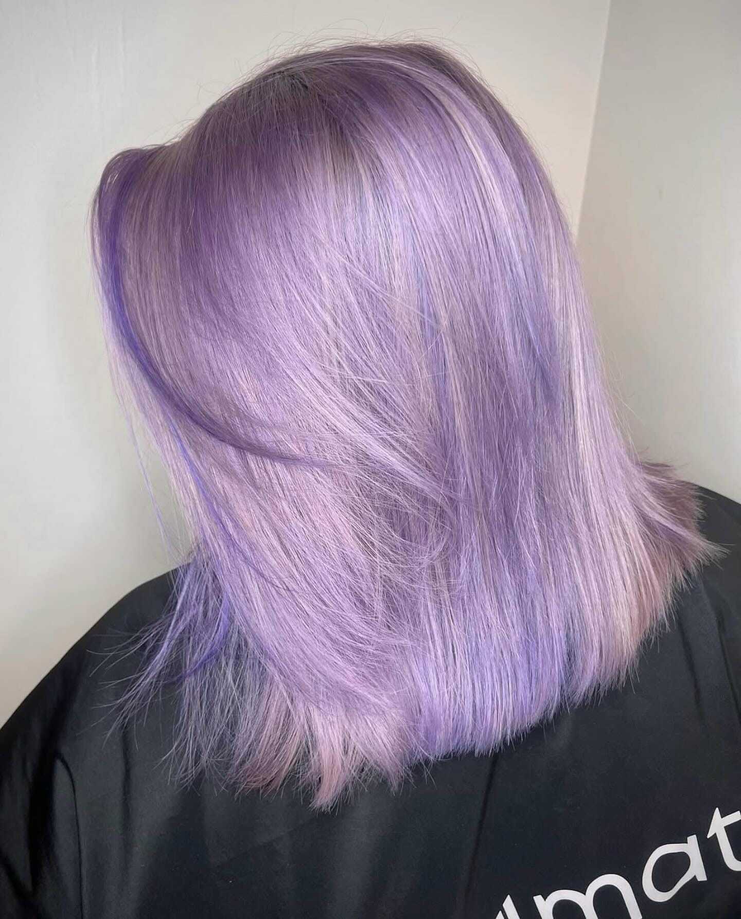 Lilac-colored hair on a person with a black salon cape.