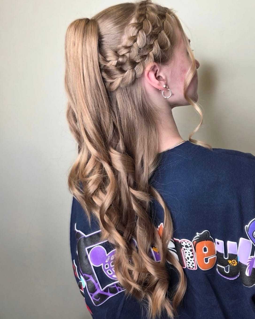 Braided ponytail hairstyle with loose curls, worn by a person in a dark Disney-themed shirt.